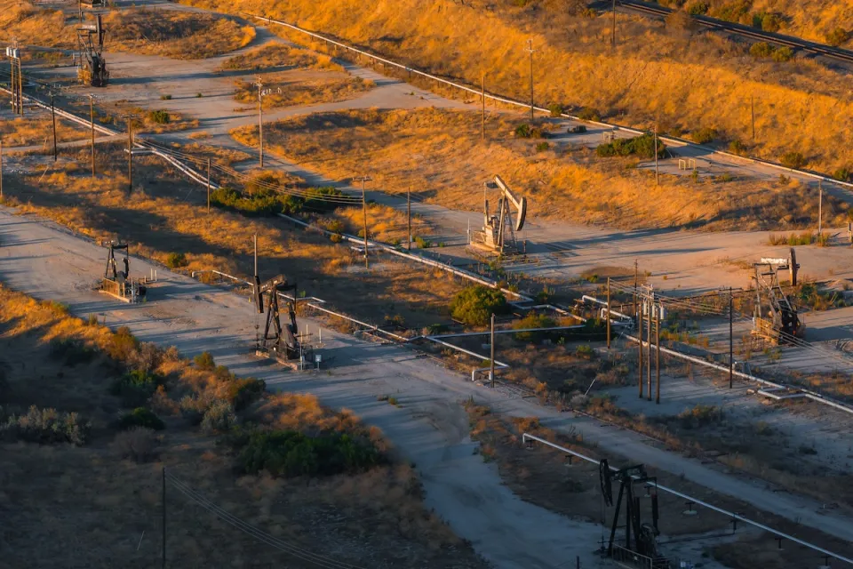 Aerial view of oil field in California with pumpjacks at sunset.